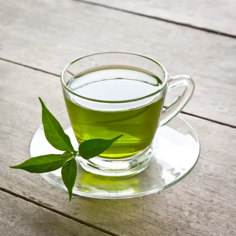 Woman drinking warm herbal tea while resting on a couch with a cold