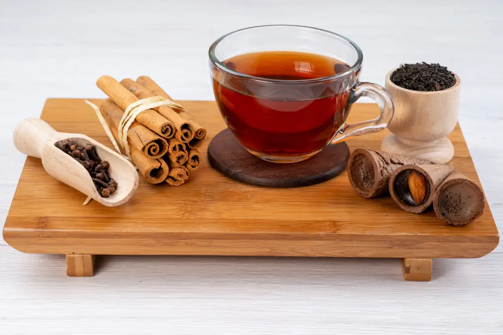 Woman drinking warm herbal tea while resting on a couch with a cold